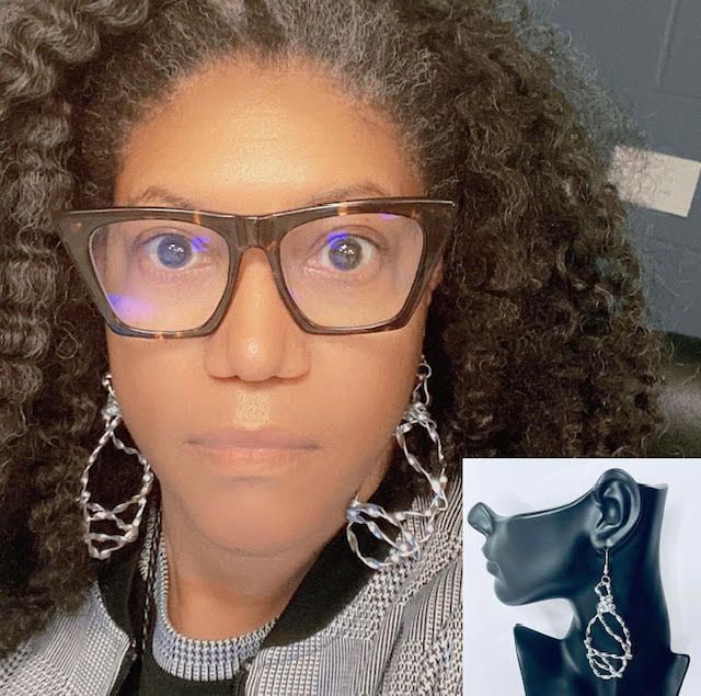 Woman wearing eyeglasses and silver wire earrings.