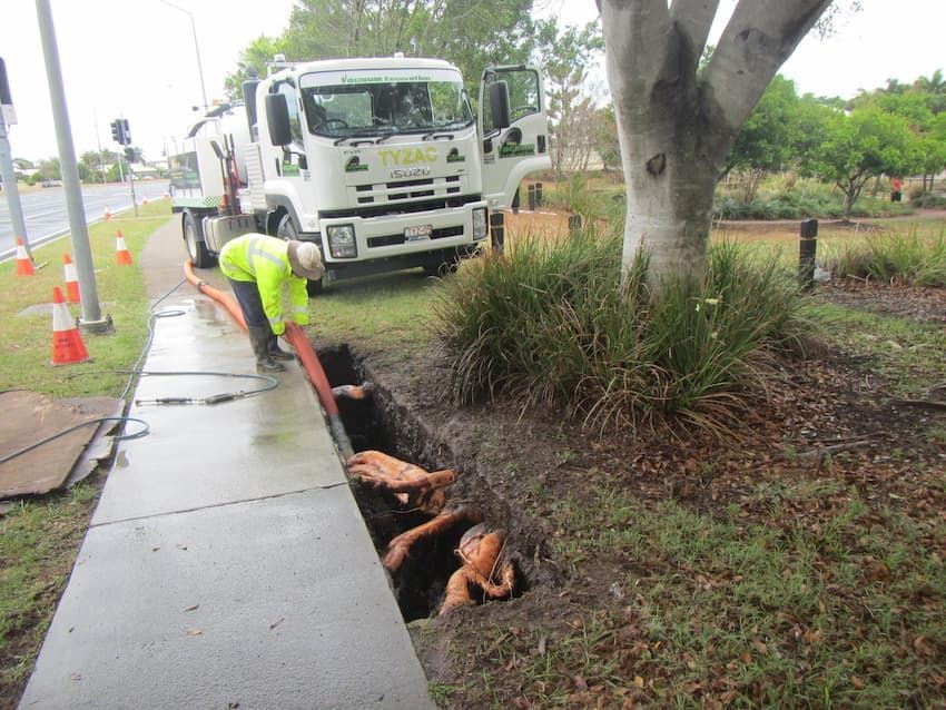 Workers Cleaning a Drainage Ditch Using a Vacuum Truck — Vacuum Excavation in Gympie, QLD