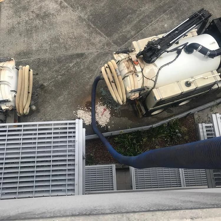 Vacuum Excavator Truck With Hose Leading Up the Side of a Building — Vacuum Excavation on the Sunshine Coast, QLD