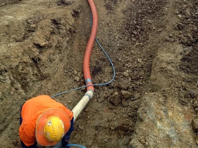 Worker Running Conduit Through a Trench — Hydro Excavation on the Sunshine Coast, QLD