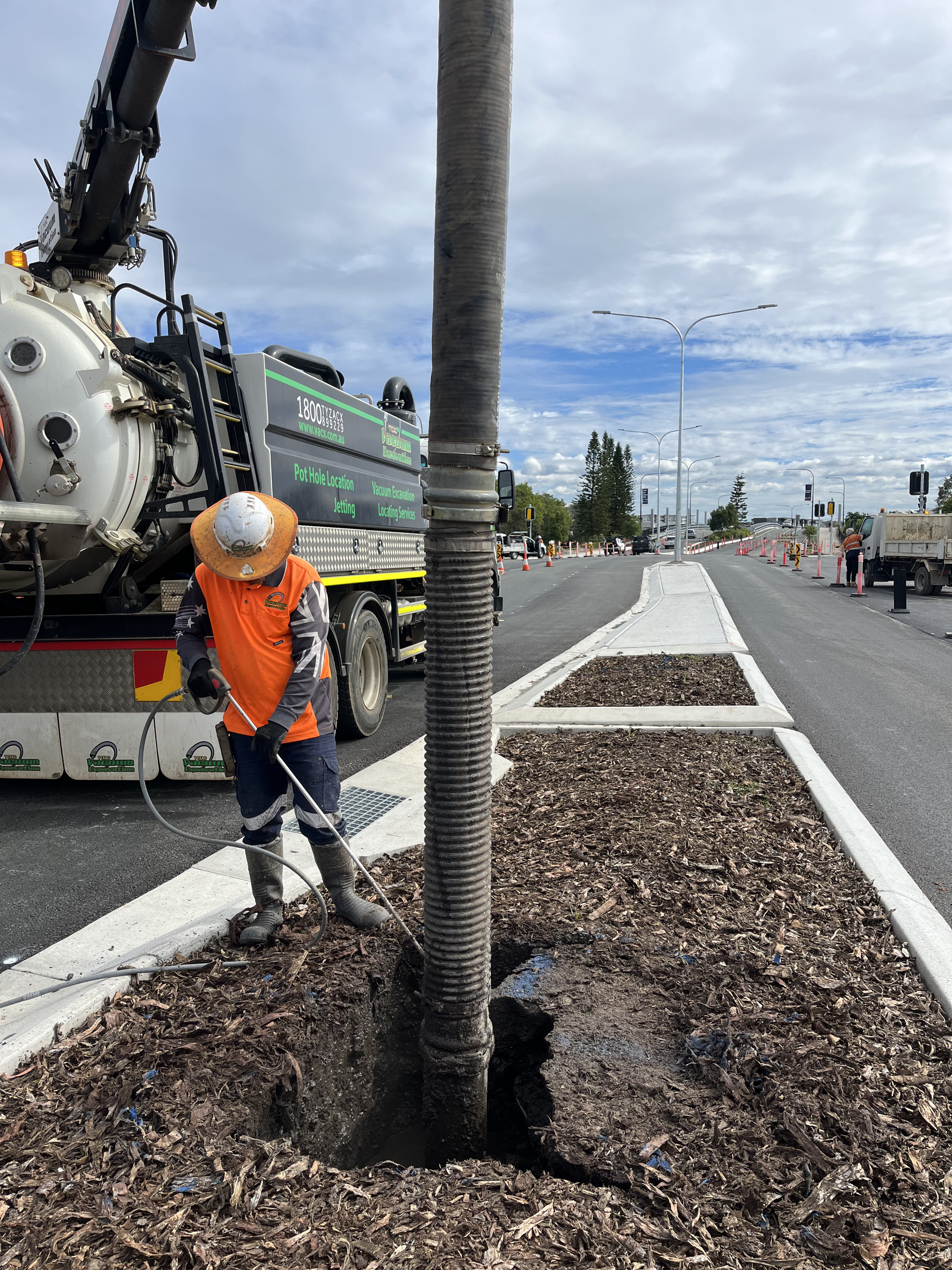 A Man Is Digging A Hole In The Ground Next To A Truck — Vacuum Excavation in Sunshine Coast, QLD