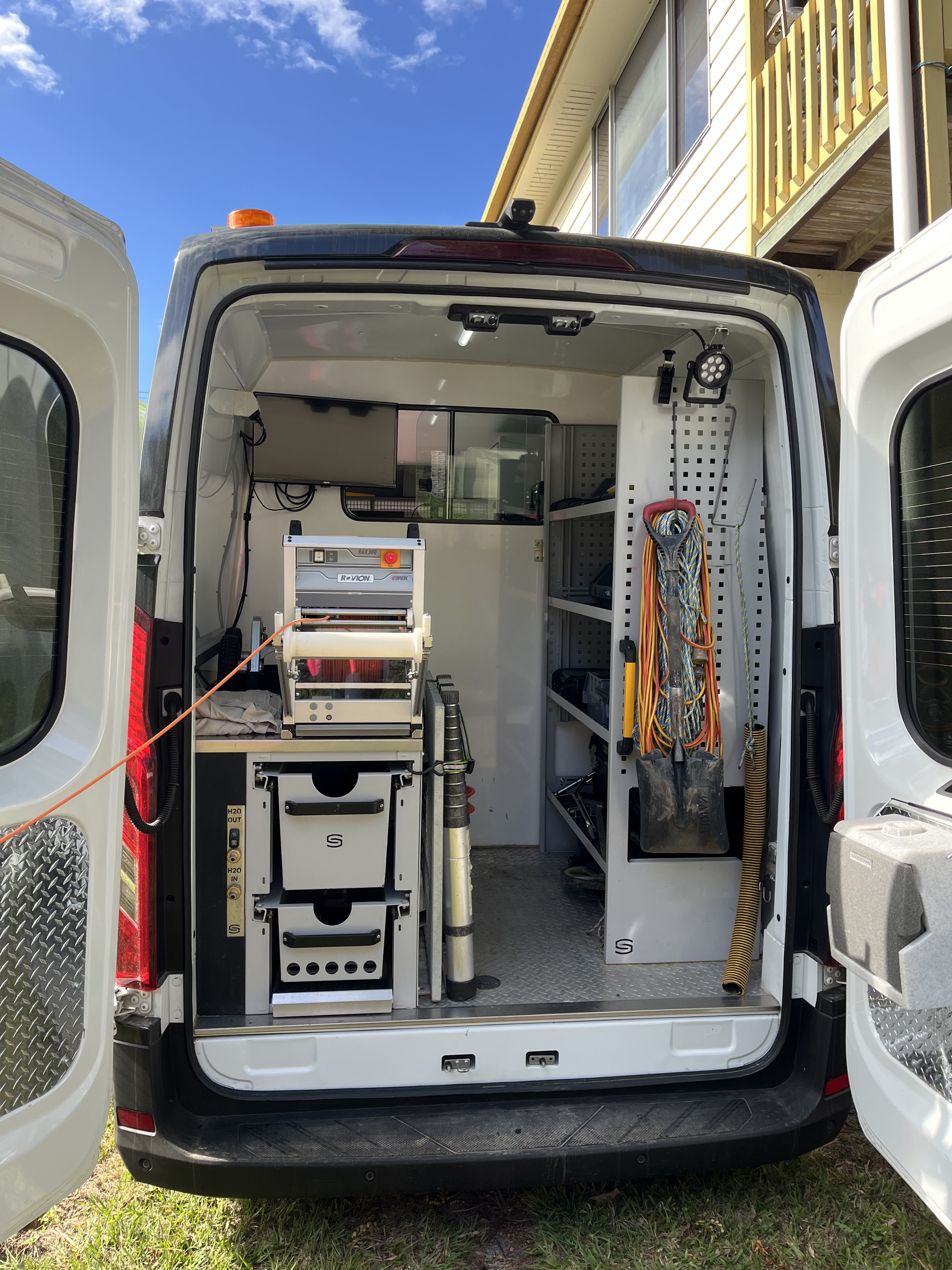 A White Van Is Parked In Front Of A Building With Its Doors Open — Vacuum Excavation in Sunshine Coast, QLD