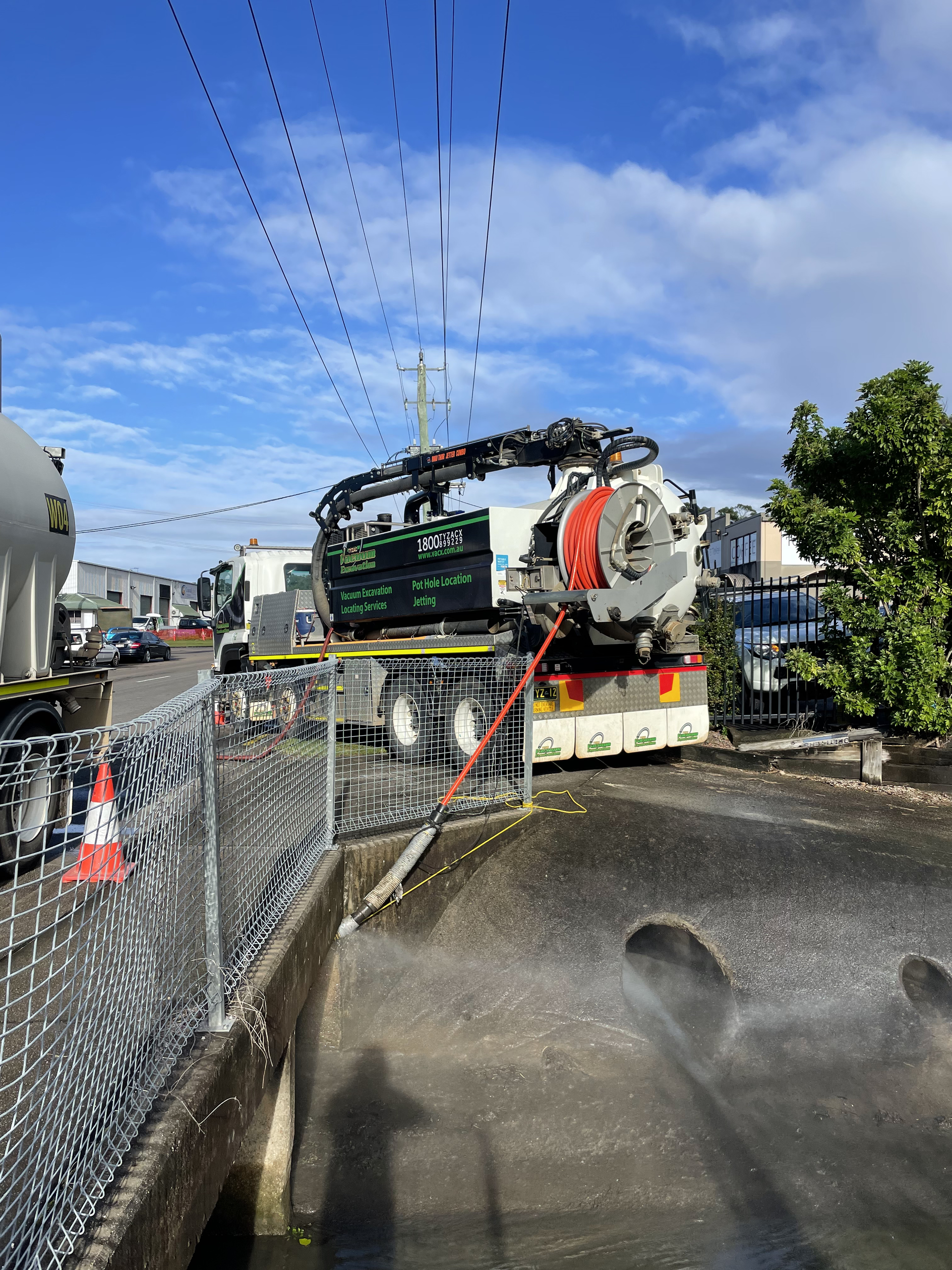A Large Machine Is Cleaning A Drain On The Side Of The Road — Vacuum Excavation in Sunshine Coast, QLD