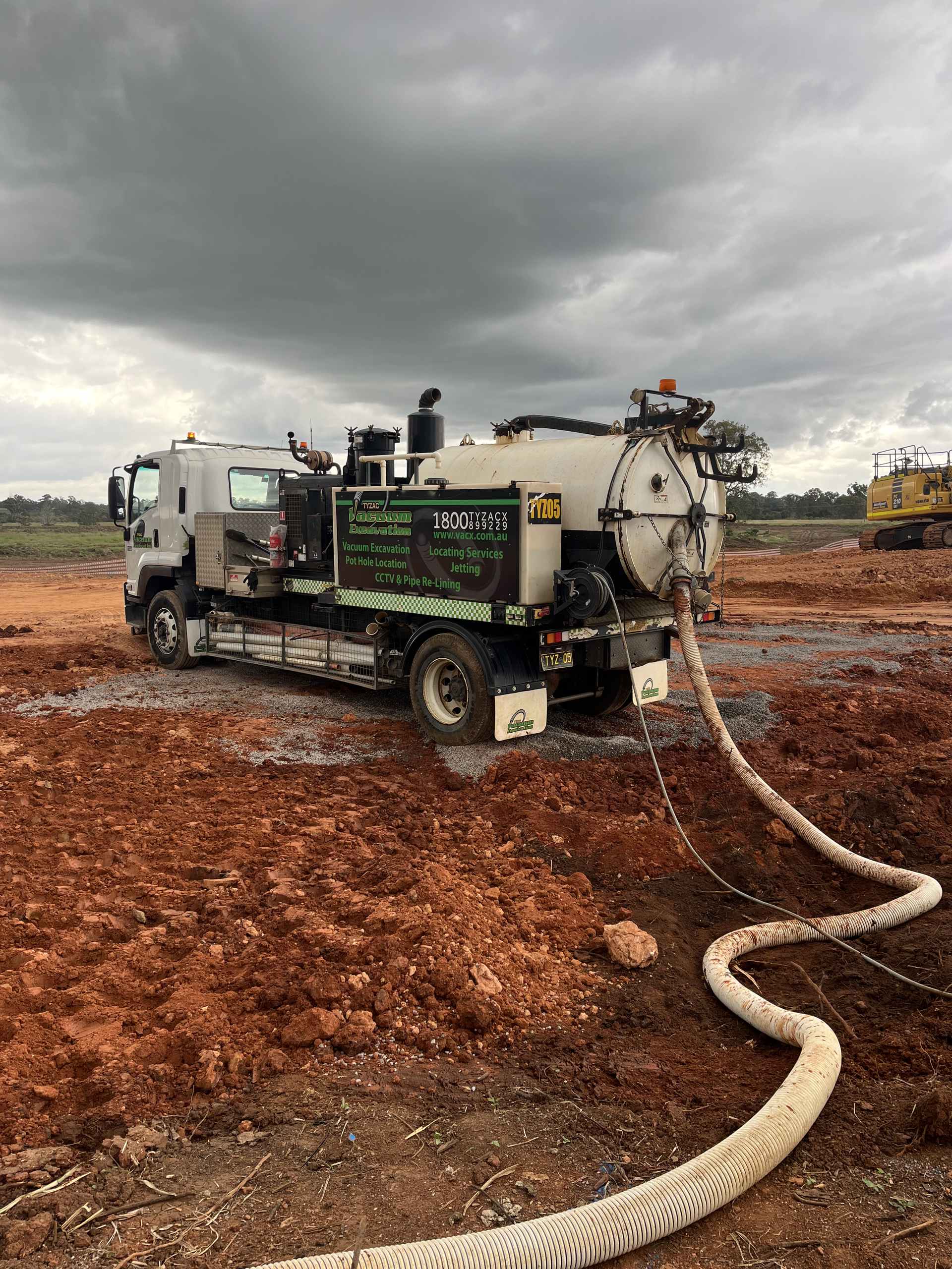A Vacuum Truck Is Sitting In The Dirt With A Hose Attached To It — Vacuum Excavation in Sunshine Coast, QLD
