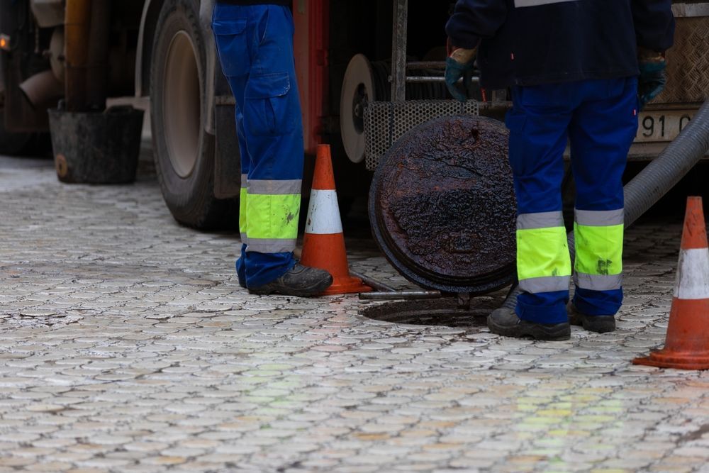 Workers Standing Around an Open Sewer Manhole — Vacuum Excavation in Hervey Bay, QLD