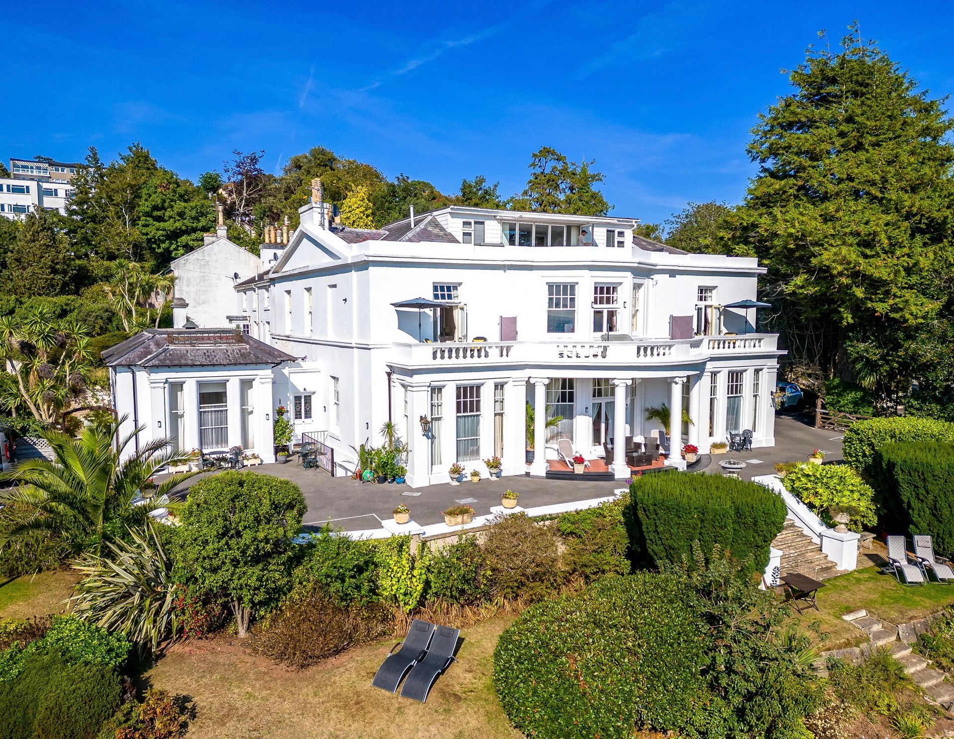Drag jester Razzle B Dazzled in colorful costume and face paint, posing with clawed hands and a wide smile.