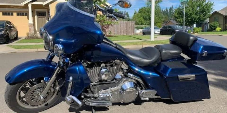 A blue harley davidson motorcycle is parked on the side of the road.