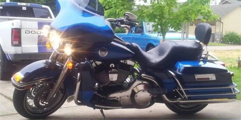 A blue harley davidson motorcycle is parked next to a dodge truck