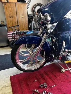 A blue motorcycle is sitting on a red rug in a garage.
