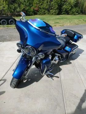 A blue harley davidson motorcycle is parked on a sidewalk.