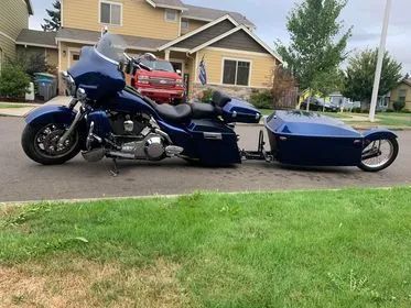 A blue motorcycle with a sidecar attached to it is parked in front of a house.