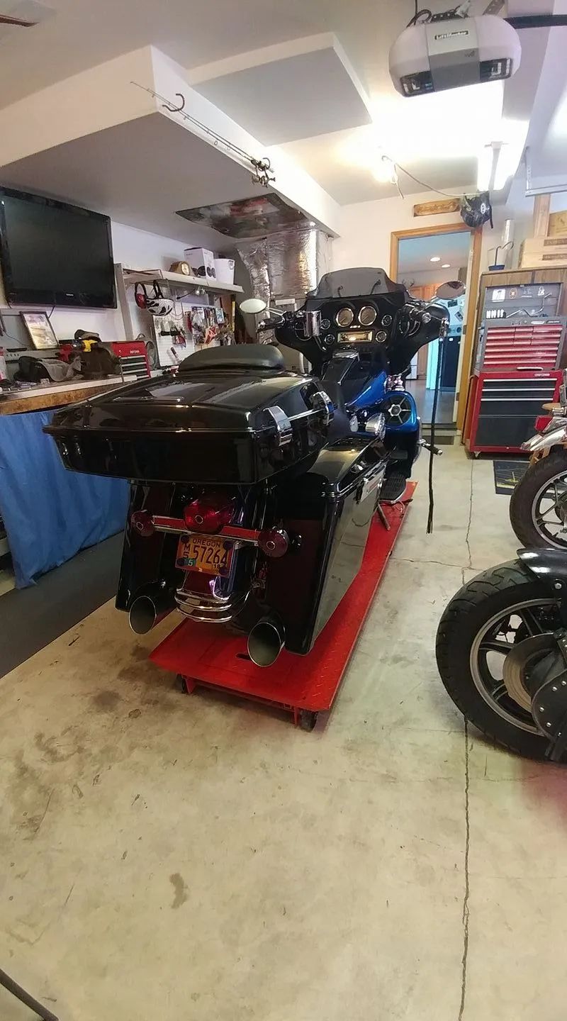 A motorcycle is sitting on top of a red cart in a garage.