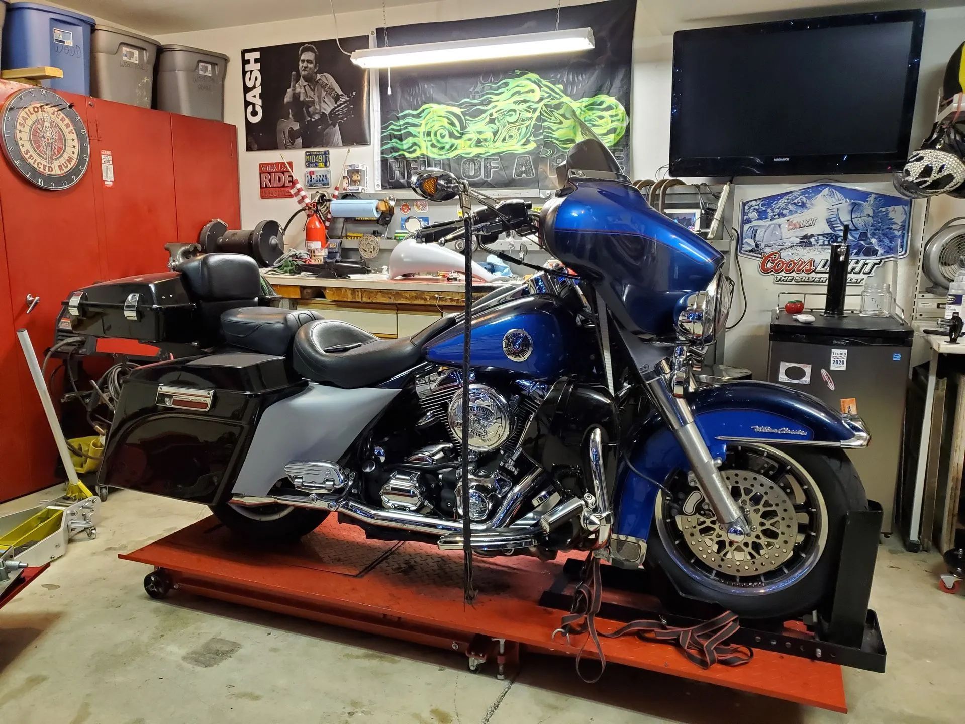A blue harley davidson motorcycle is parked on a lift in a garage.