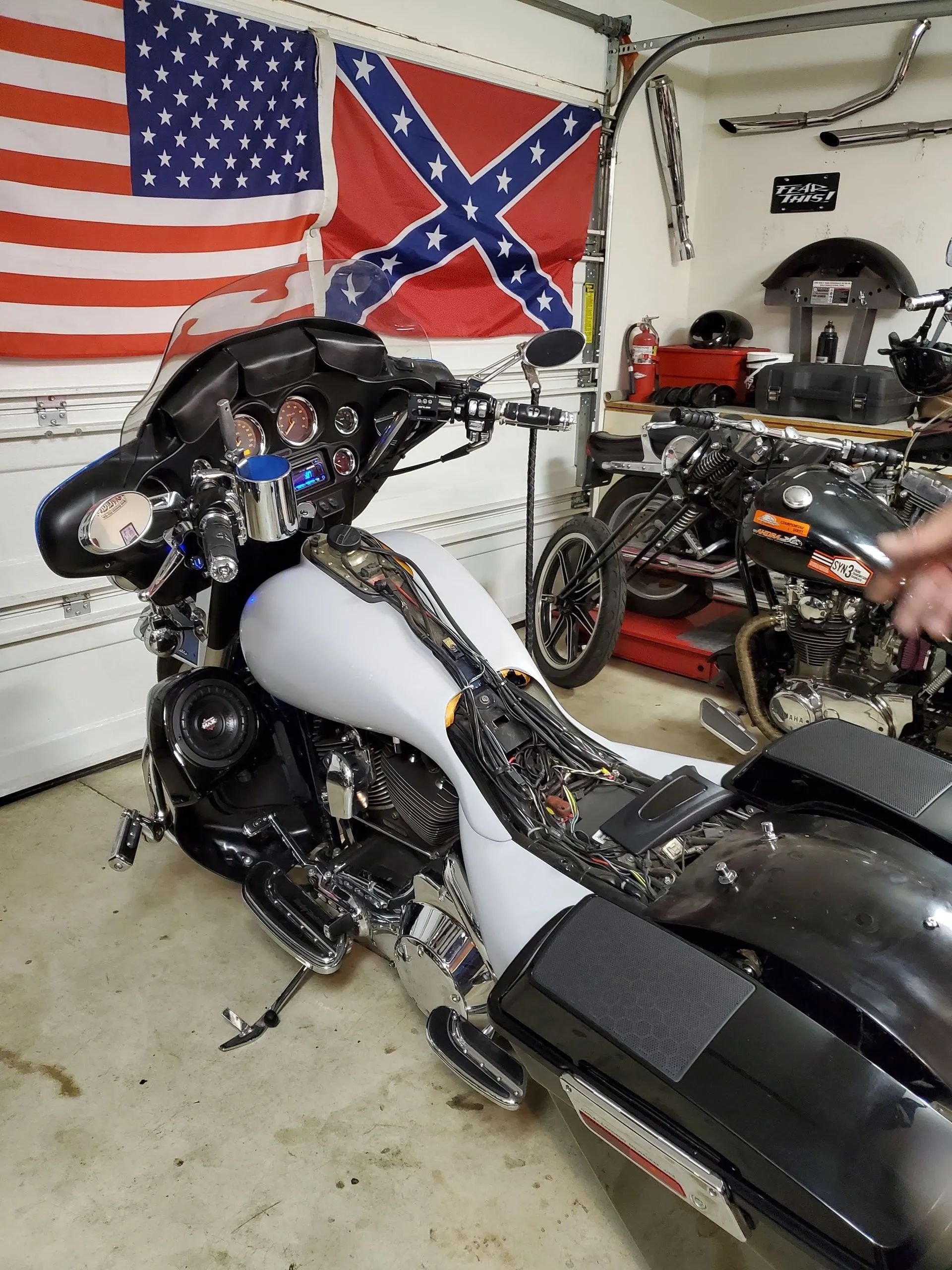 A motorcycle is parked in a garage with an american flag behind it