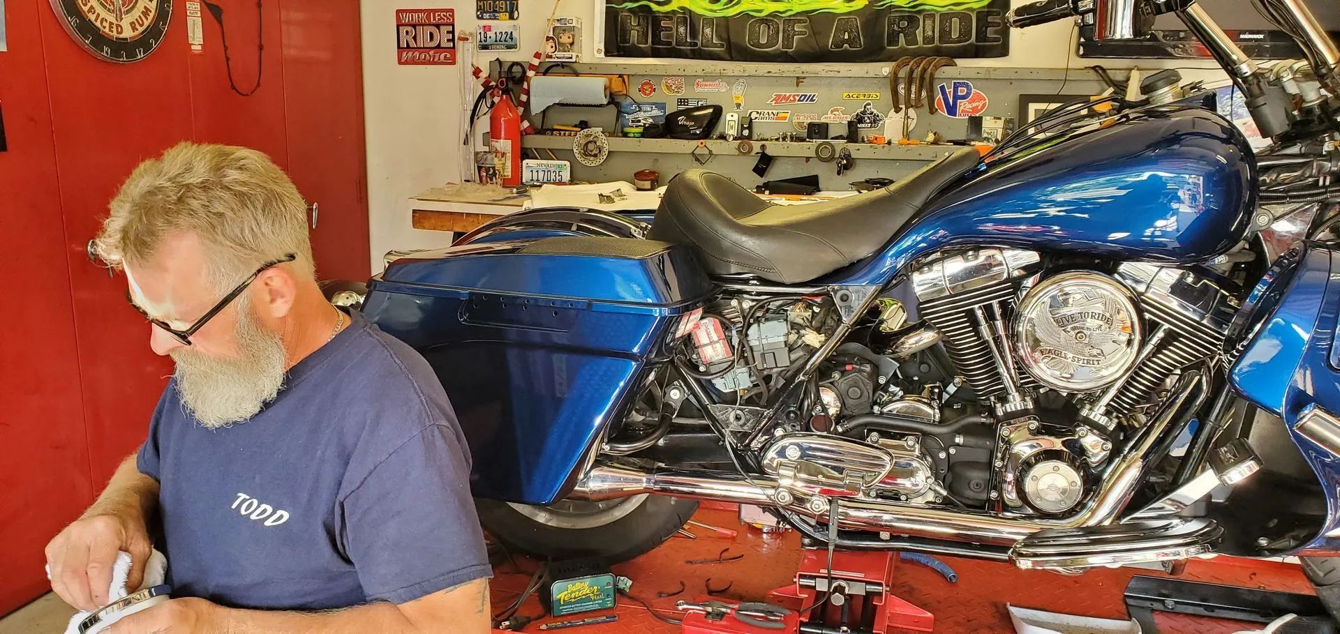 A man is working on a blue motorcycle in a garage.