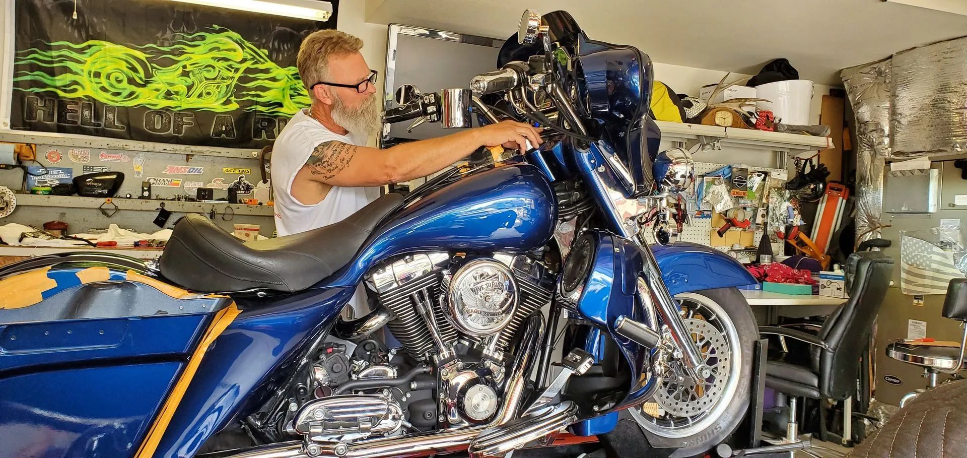 A man is working on a blue harley davidson motorcycle in a garage.