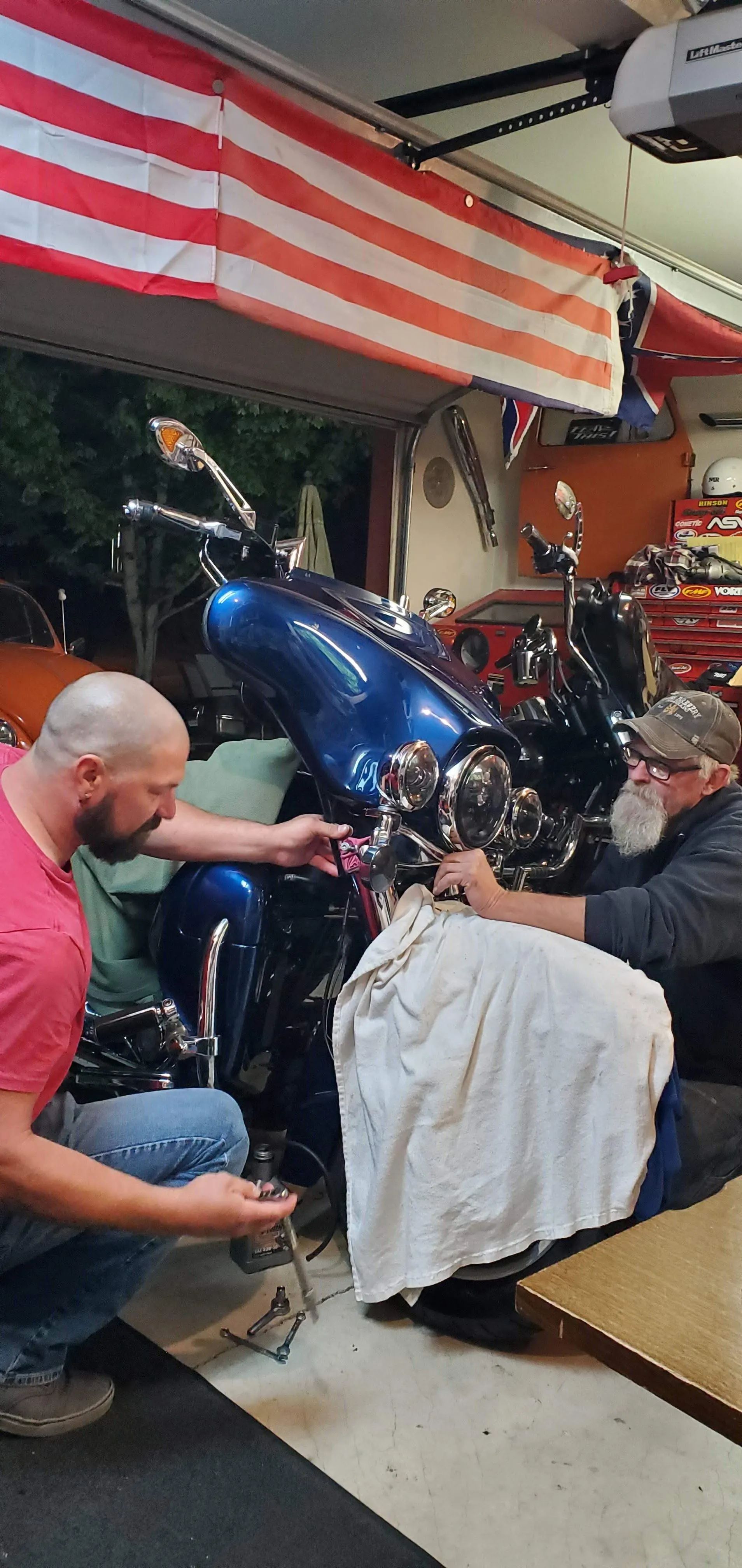 Two men are working on a motorcycle in a garage.