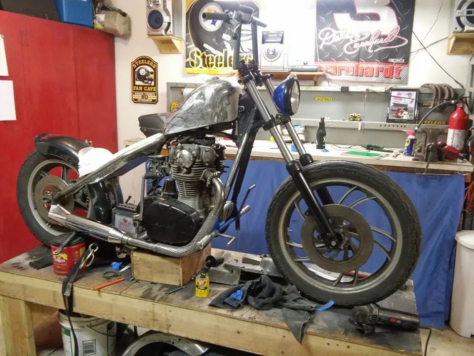 A motorcycle is sitting on a wooden table in a garage