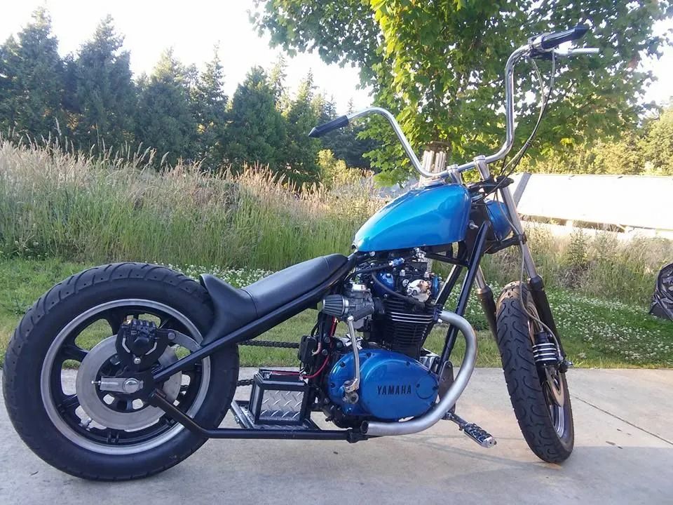 A blue yamaha motorcycle is parked on the side of the road.