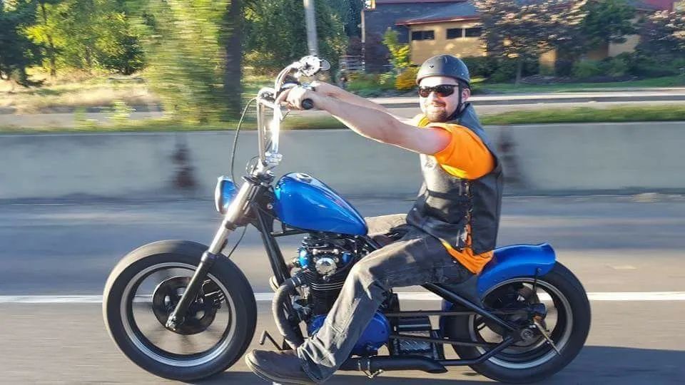 A man is riding a blue motorcycle on a highway.