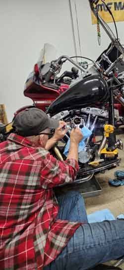 A man is working on a motorcycle in a garage.