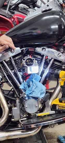 A person is working on a motorcycle engine in a garage.