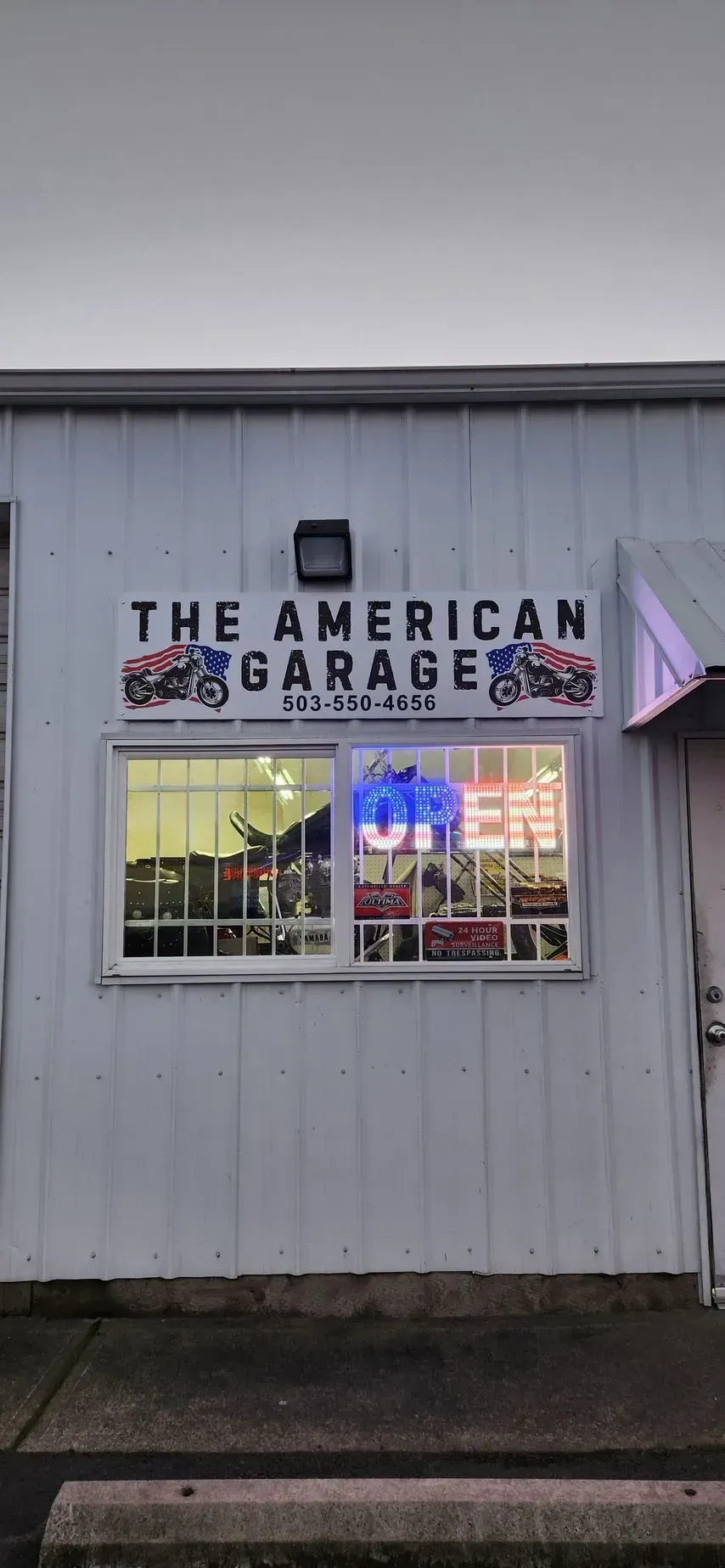 A white building with a window and a sign that says `` the american garage ''.