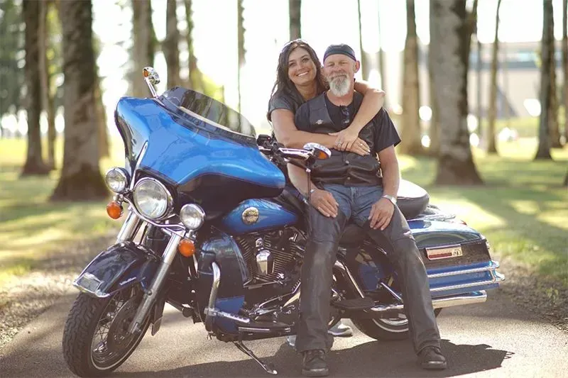 A man and a woman are sitting on a blue motorcycle.
