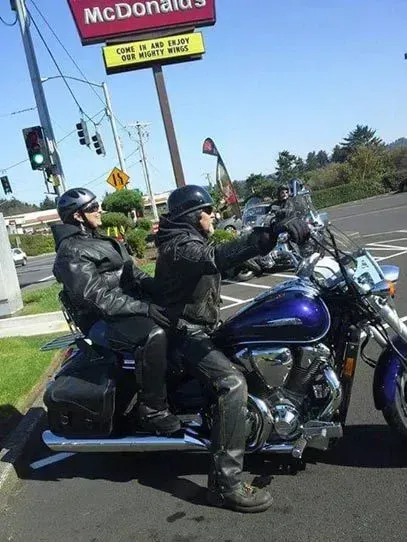 Two men are riding a motorcycle in front of a mcdonald 's sign