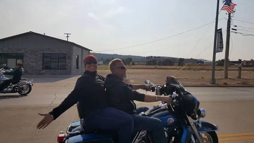 Two men are riding motorcycles down a street.