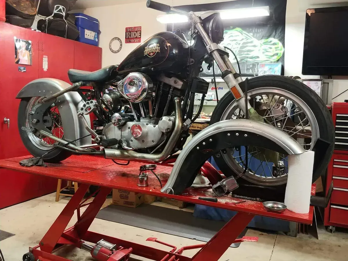 A motorcycle is sitting on a lift in a garage.