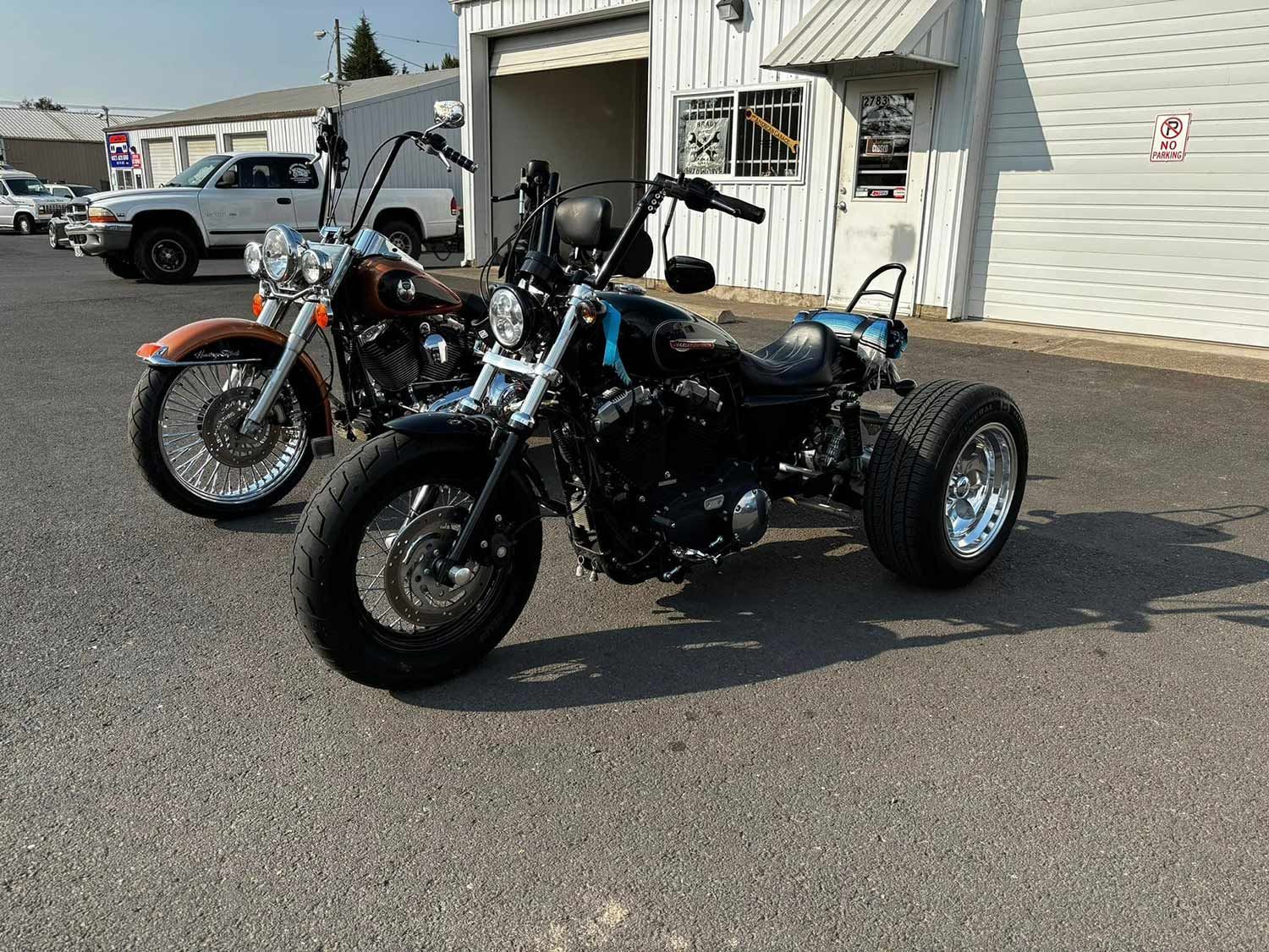 Two motorcycles are parked next to each other in front of a garage.
