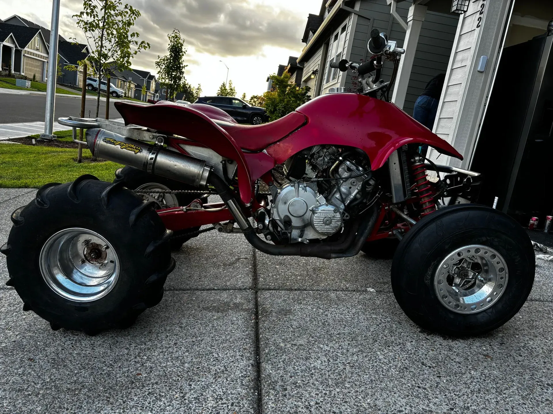 A red atv is parked in front of a garage