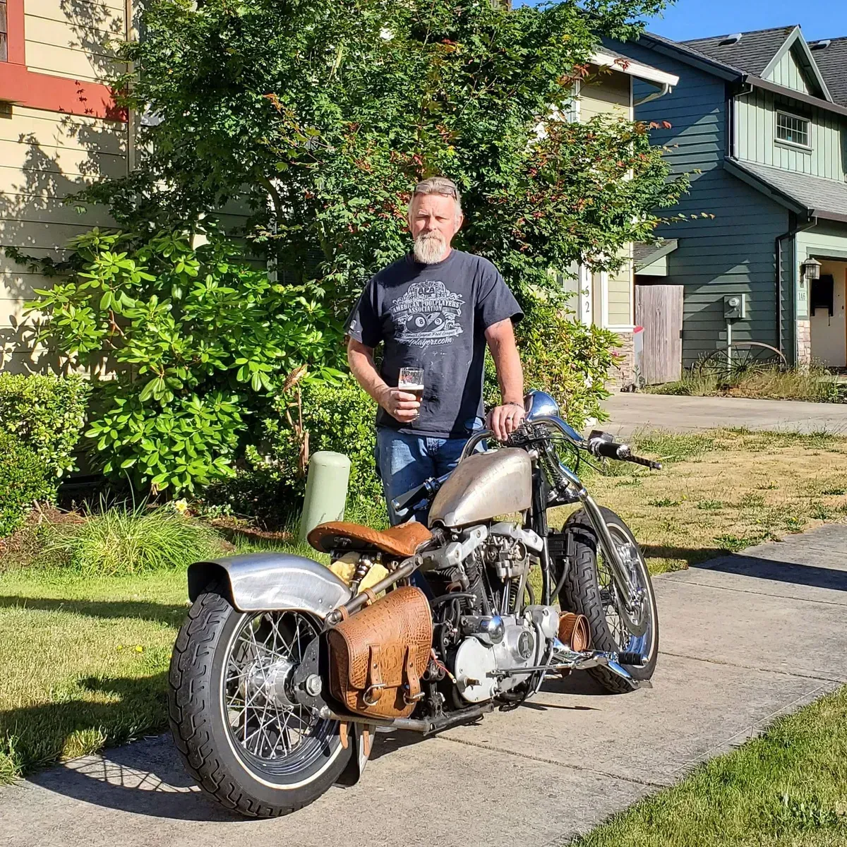 A man is standing next to a motorcycle on a sidewalk.