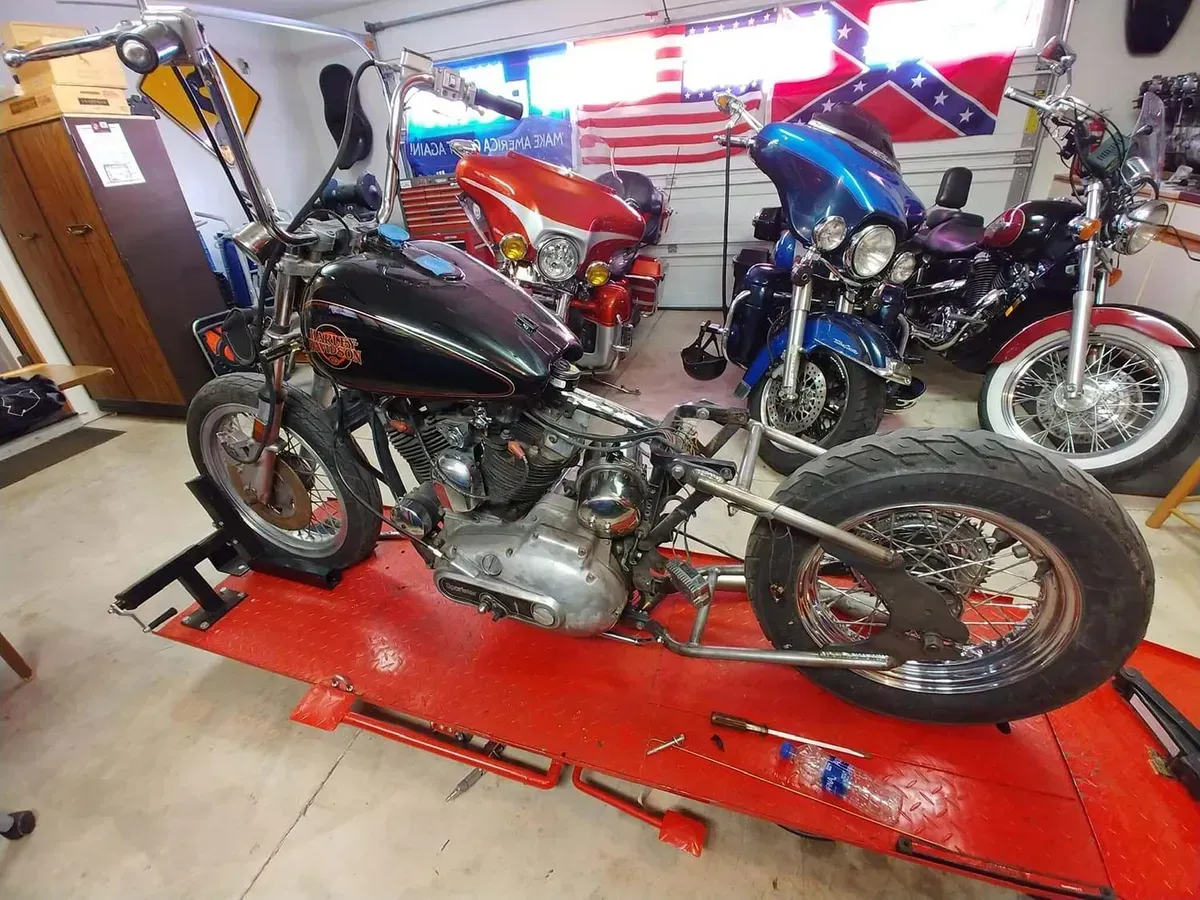 A motorcycle is sitting on a red table in a garage.