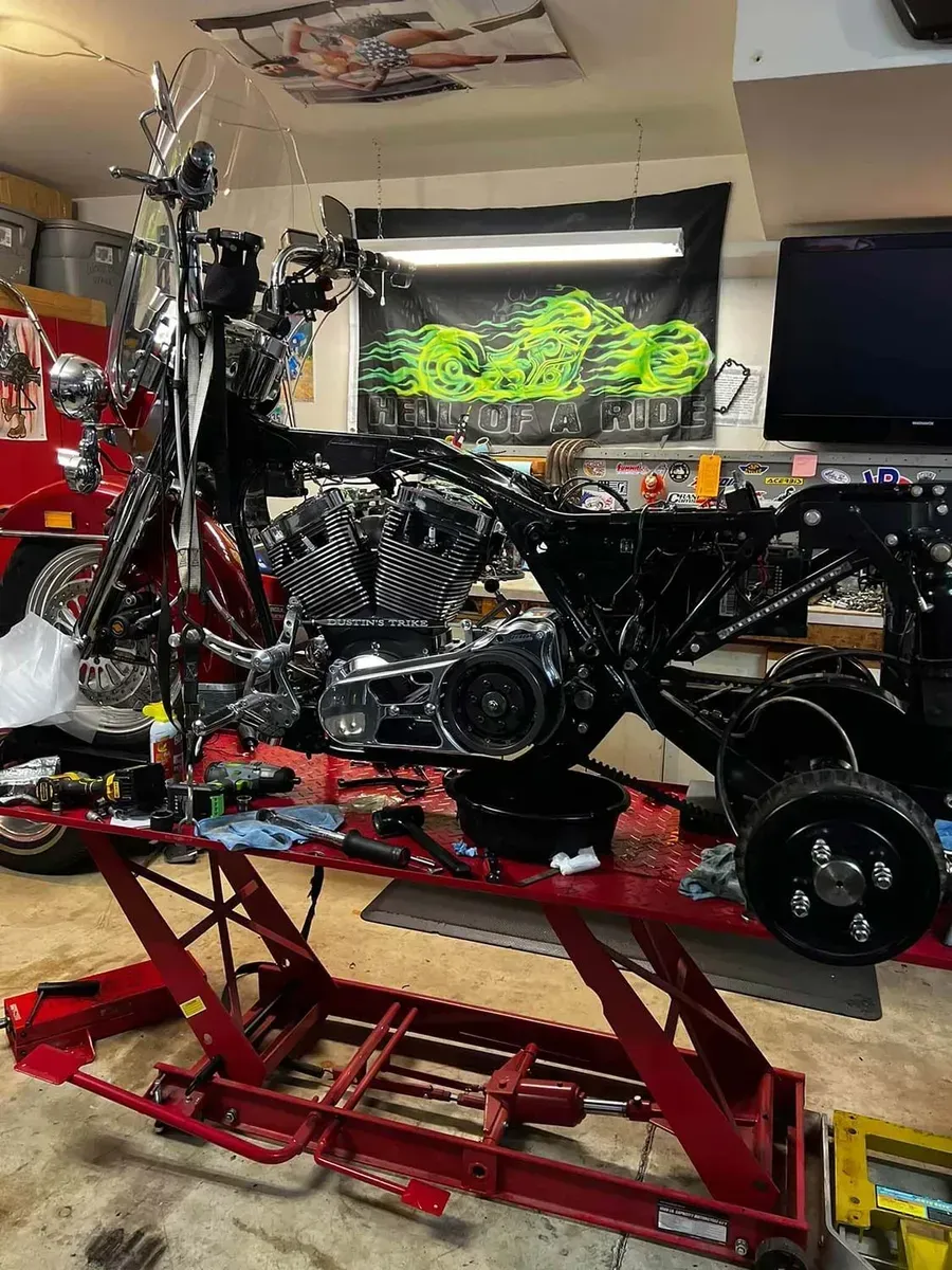 A motorcycle is being worked on on a lift in a garage.