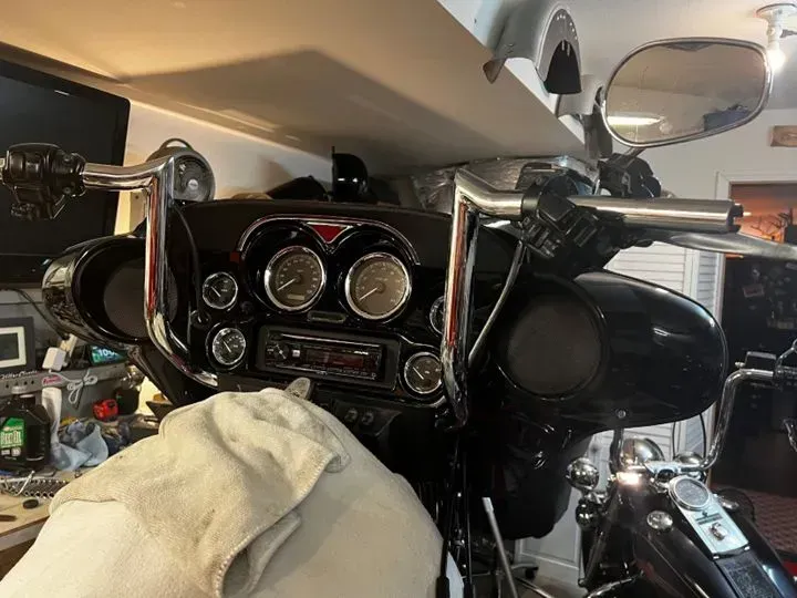 A motorcycle is parked in a garage with a towel on the dashboard.