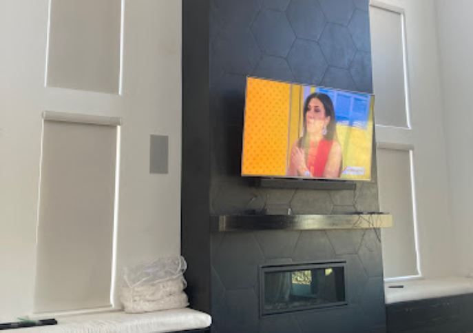 A television is hanging on the wall above a fireplace in a living room.
