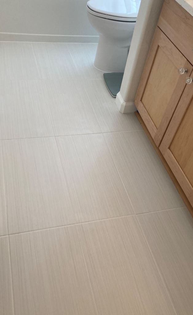 A bathroom with a toilet , sink , and cabinets.