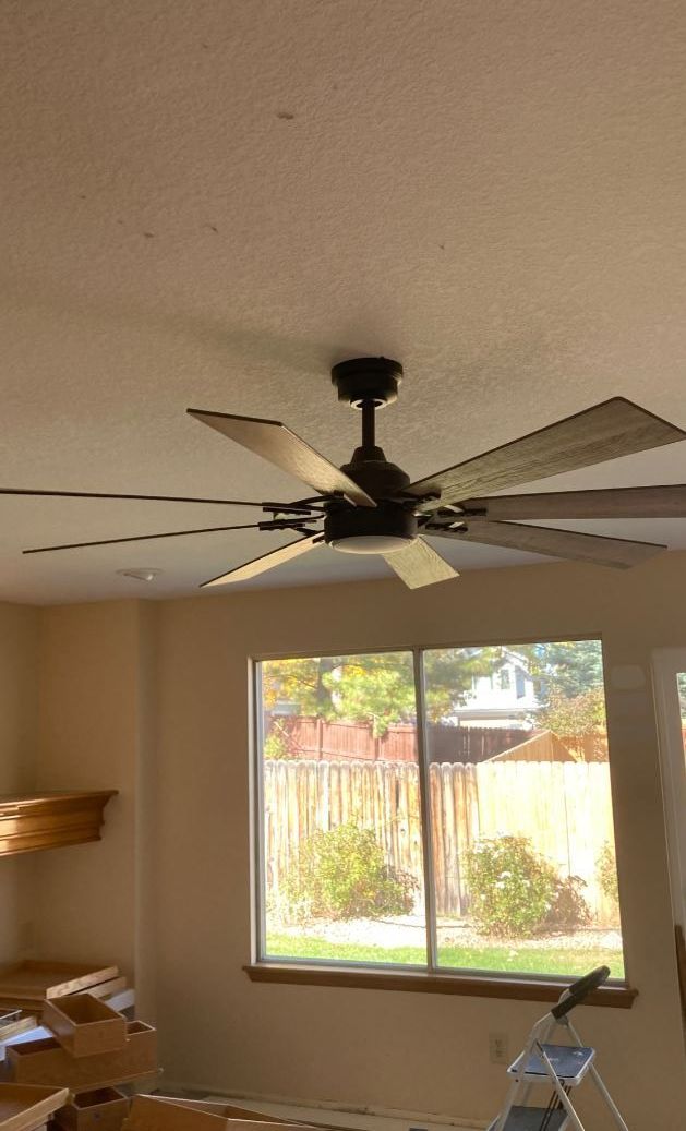 A ceiling fan is hanging from the ceiling of a living room next to a window.