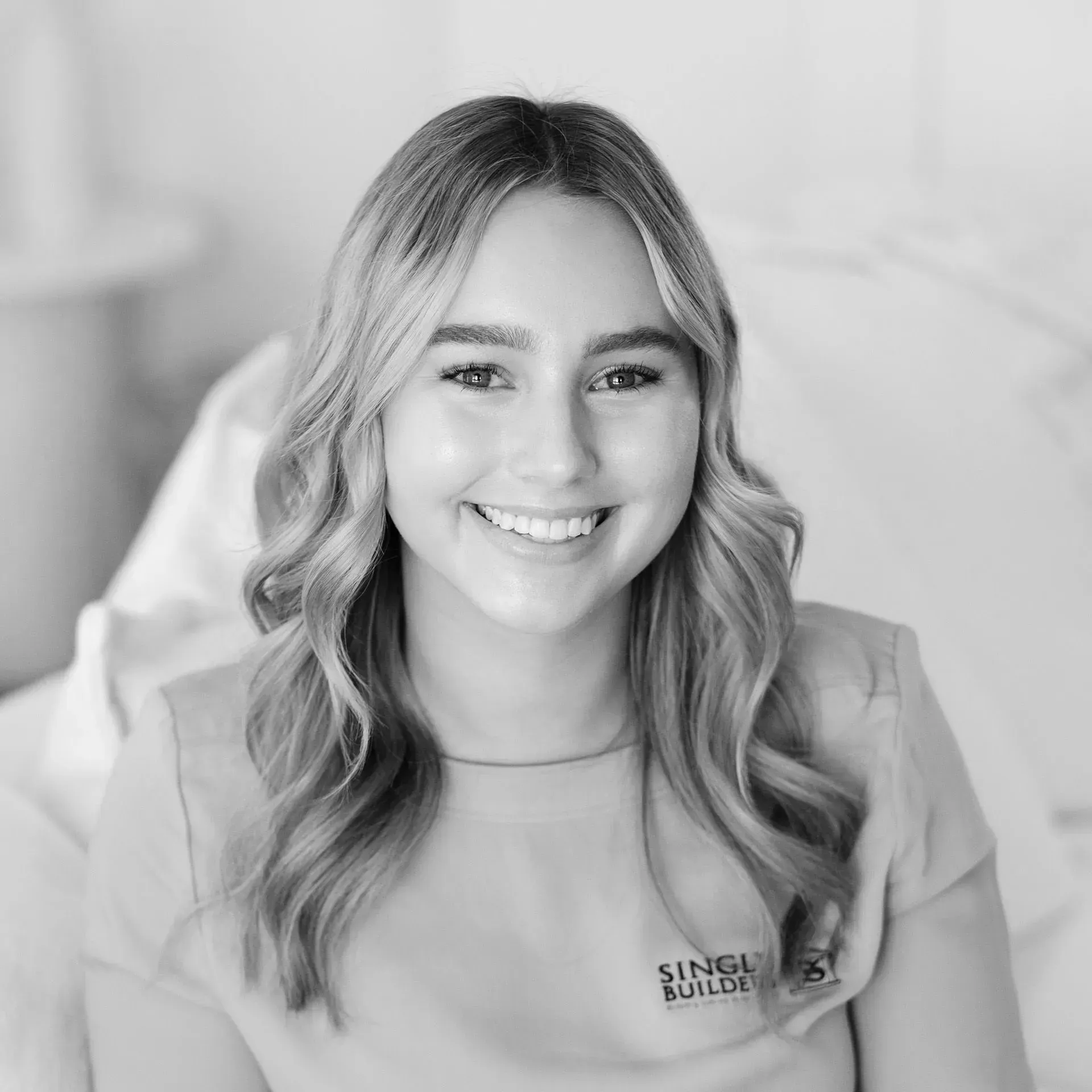 A woman is smiling in a black and white photo.