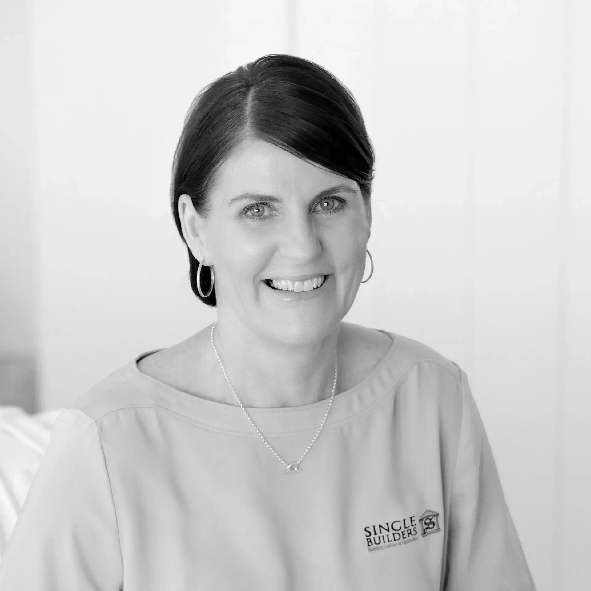 A black and white photo of a woman wearing a necklace and smiling.