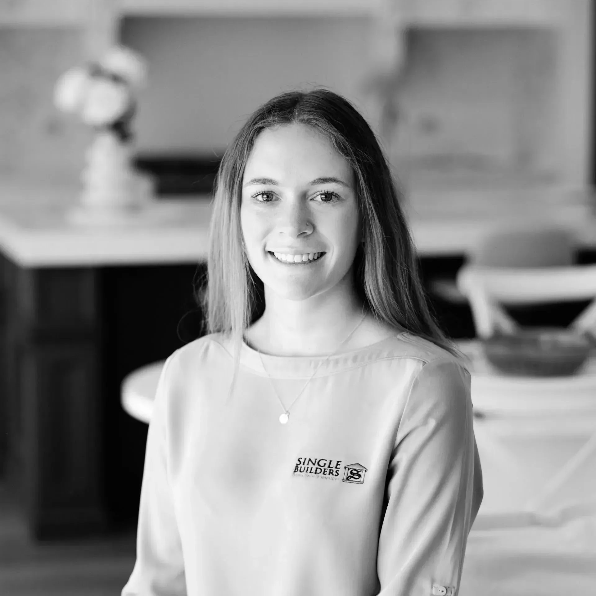 A black and white photo of a woman smiling in a kitchen.