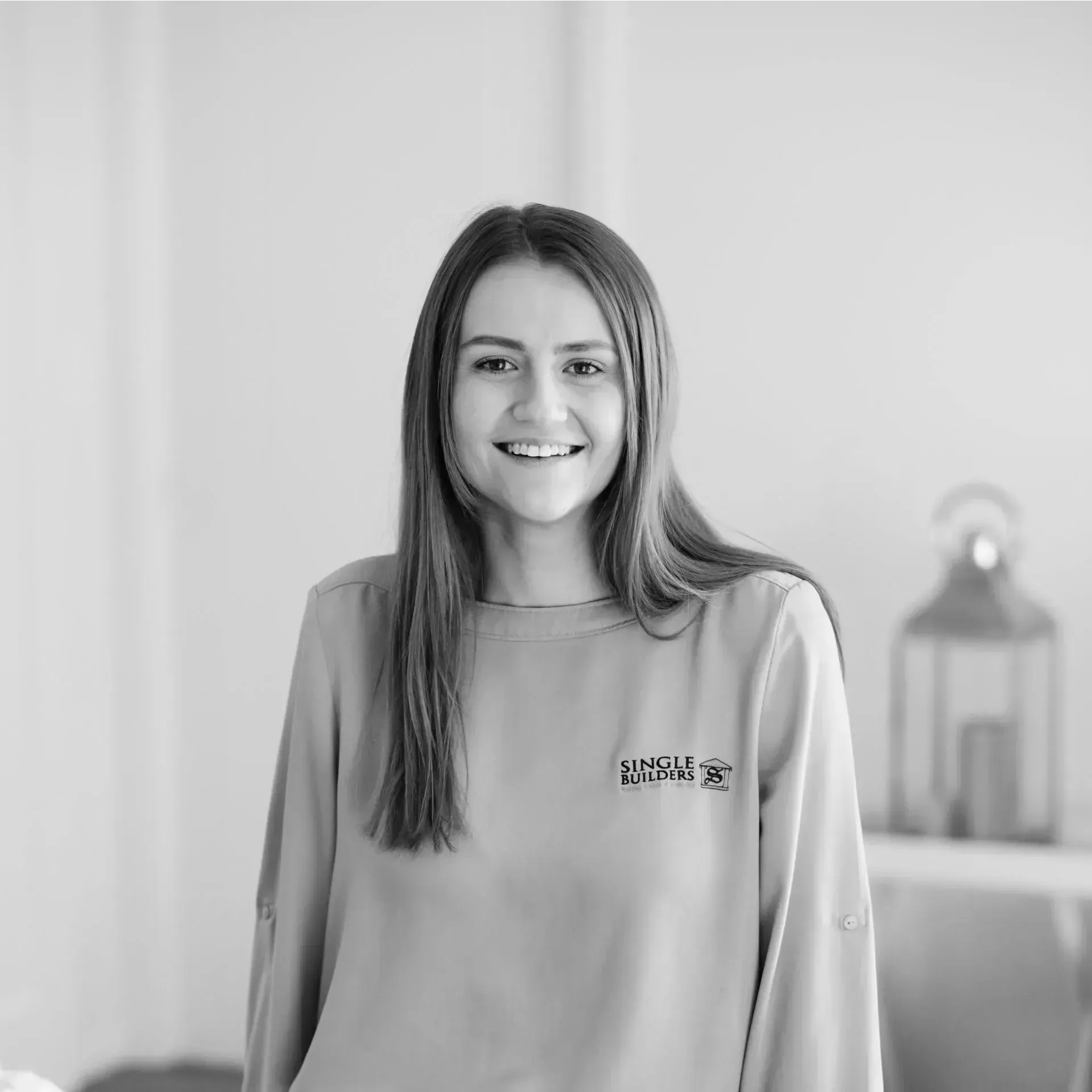 A black and white photo of a woman wearing a sweater and smiling.