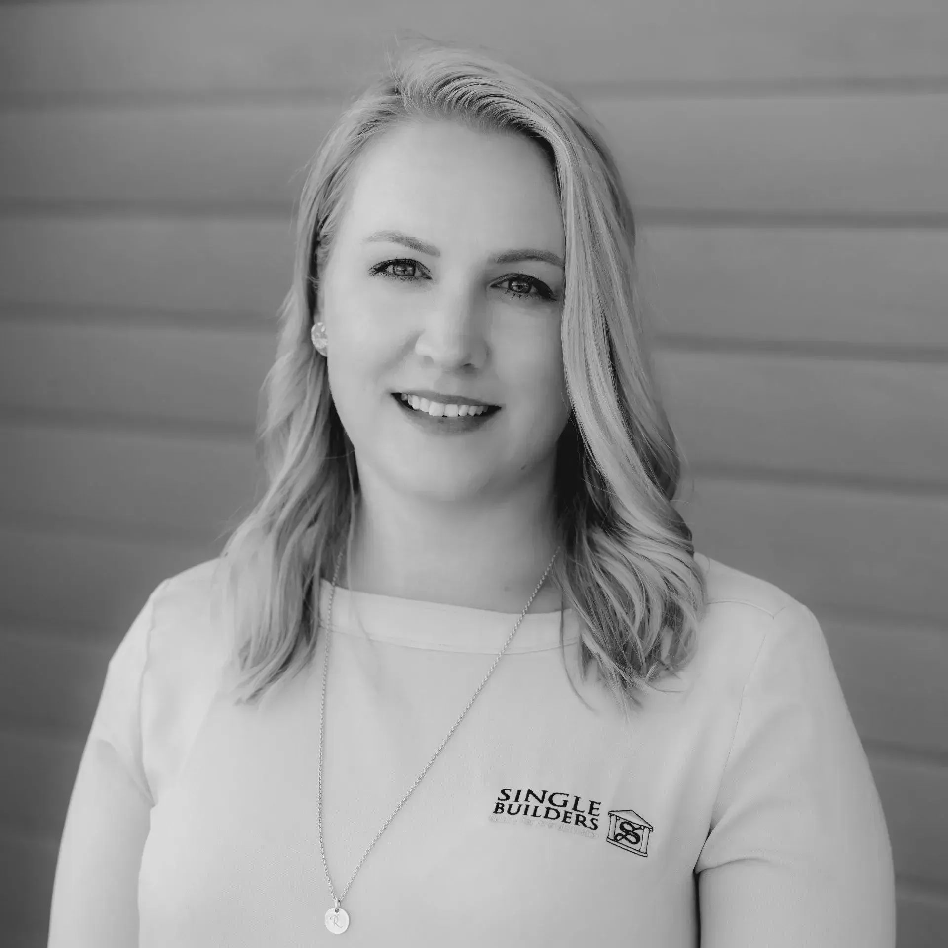 A black and white photo of a woman wearing a necklace and smiling.