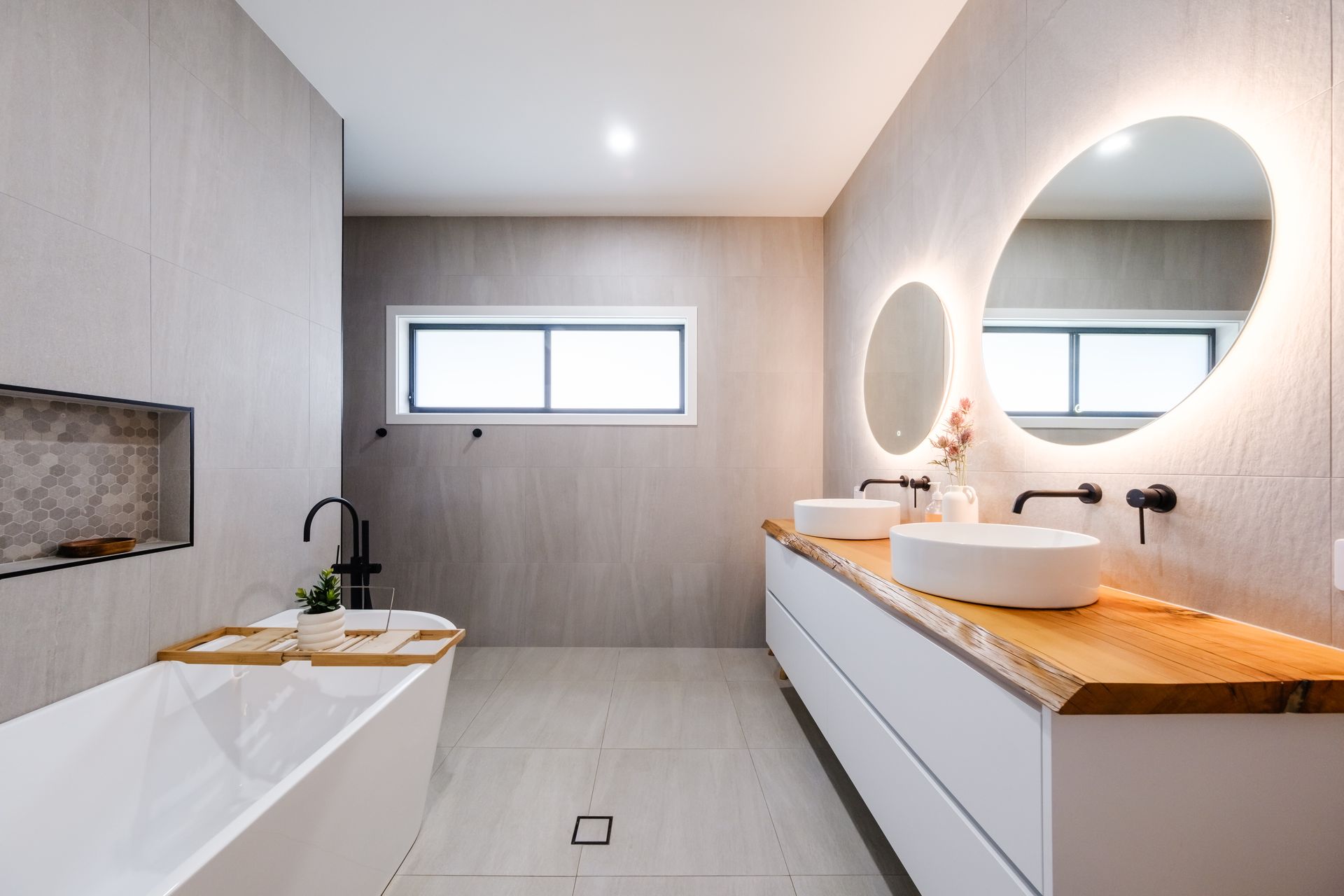 A bathroom with two sinks , a bathtub and two mirrors.