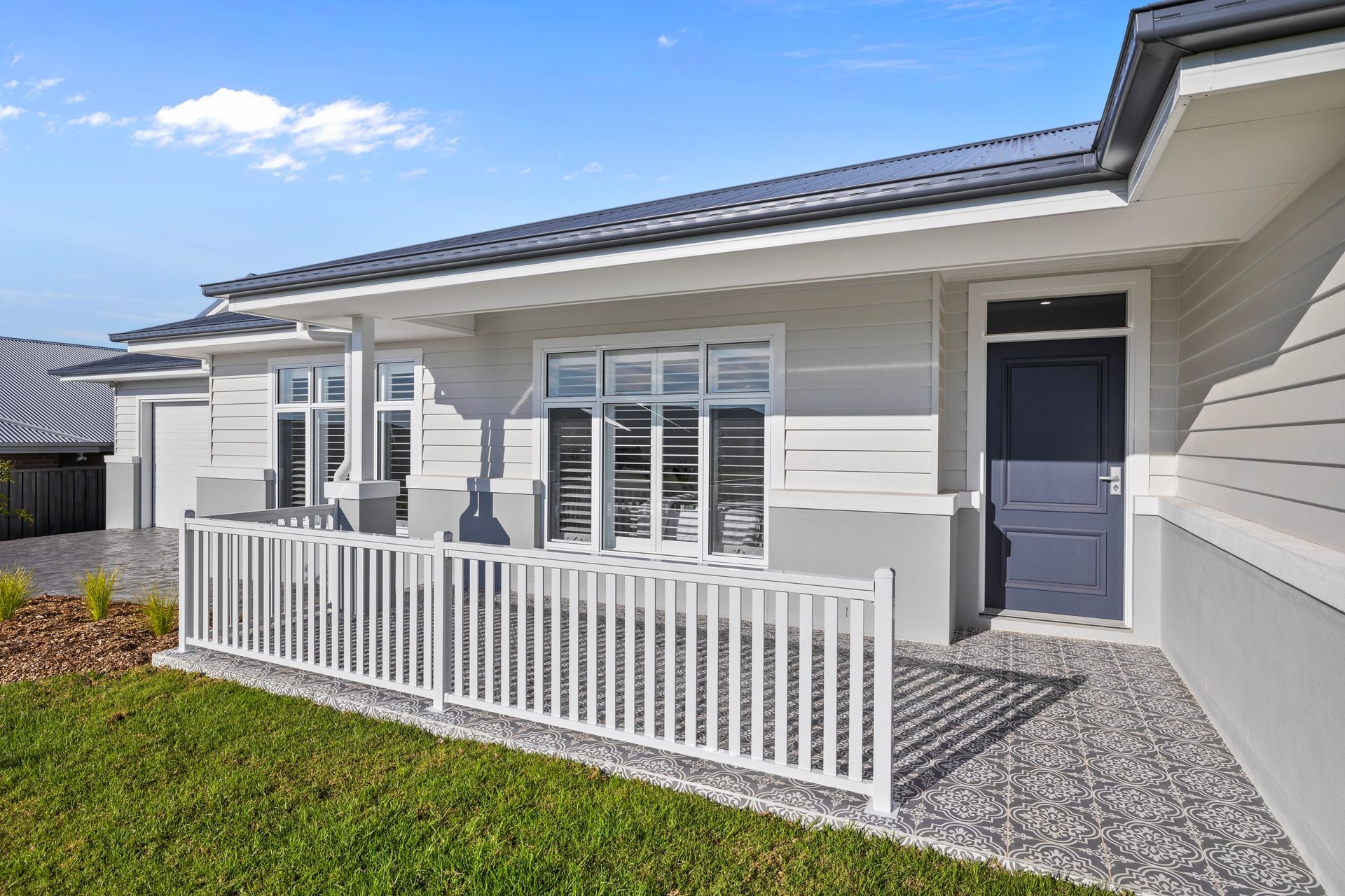 The front of a house with a white fence and a blue door.
