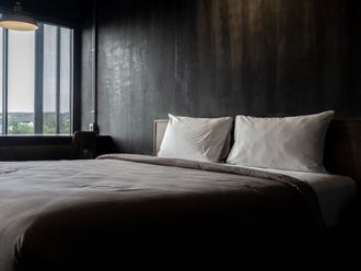 a bed with white sheets and pillows in a dark room