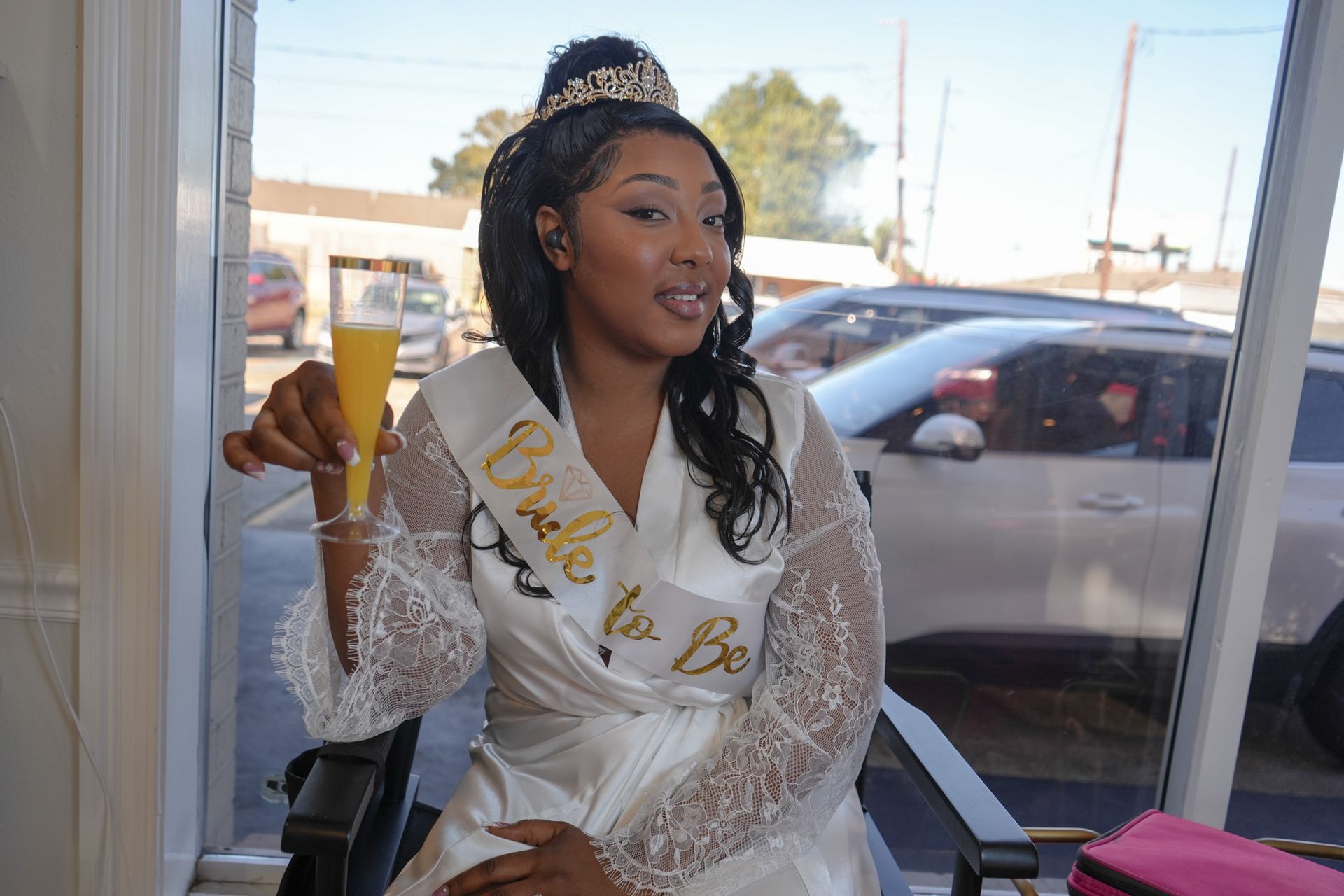 A woman in a bride to be robe is holding a glass of champagne.