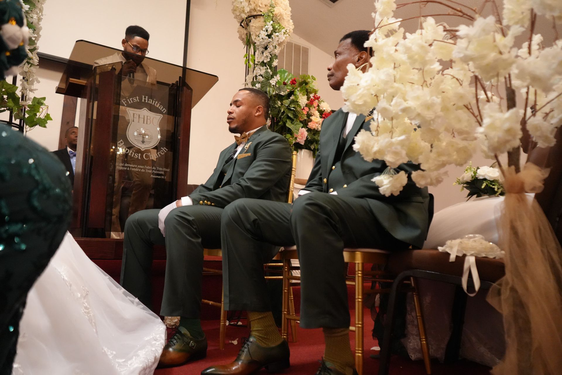 A bride and groom are sitting in front of a podium at a wedding ceremony.